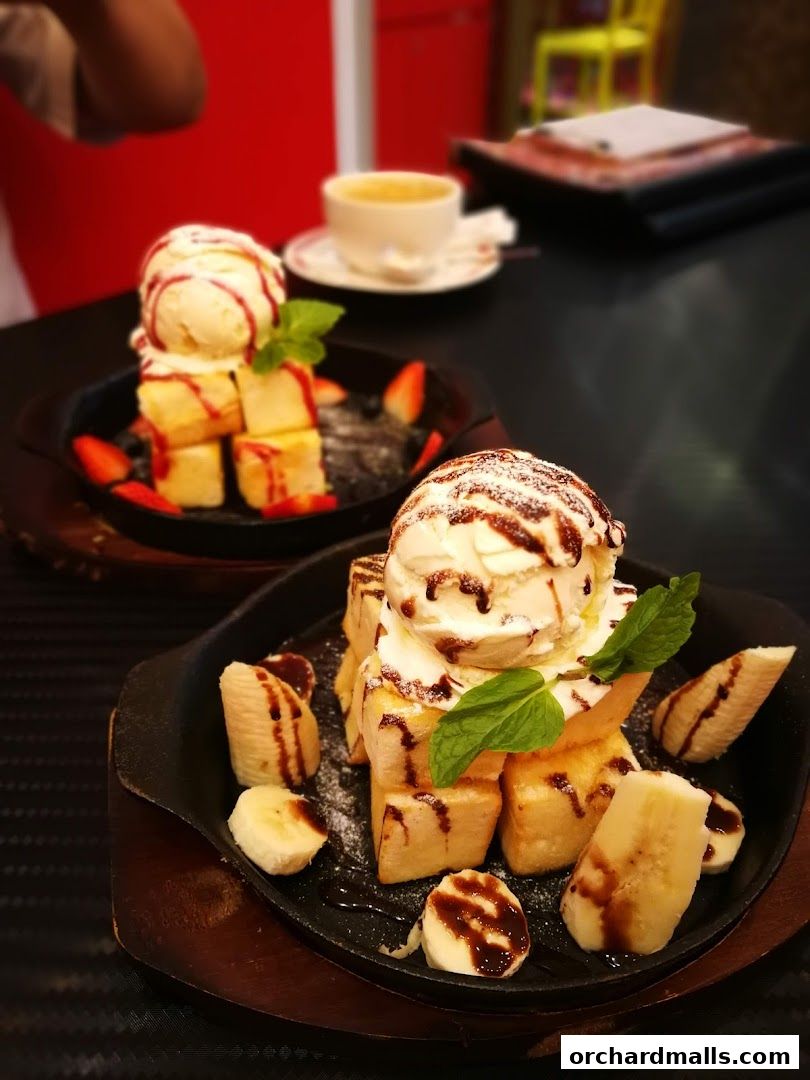 Two delicious desserts with ice cream, toast, fruits, and chocolate sauce.