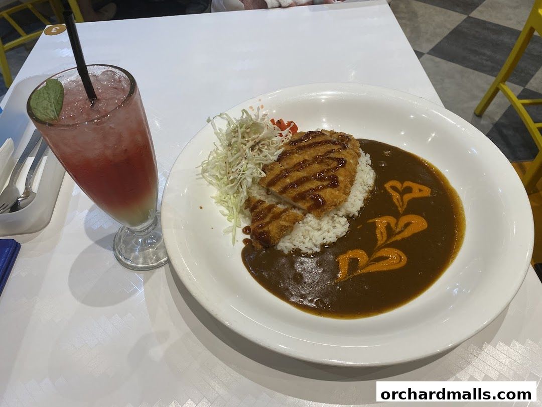 A plate of Japanese curry with katsu and a refreshing drink.