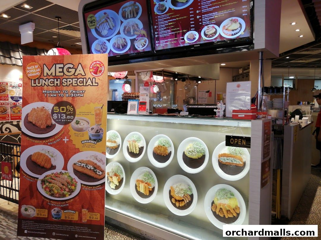 A Monster Curry shop front with a large promotional banner for a lunch special and display of curry dishes.