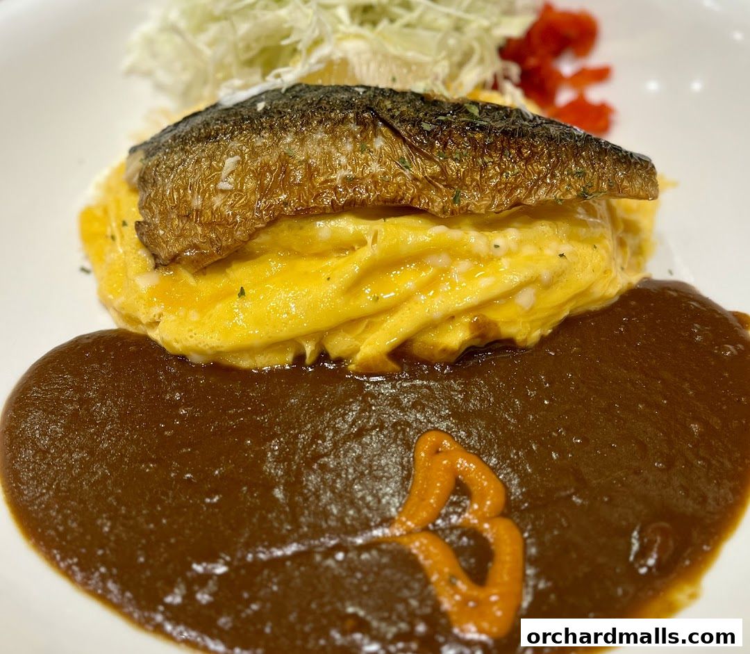 A close-up of a Japanese curry dish with grilled fish, omelet, and sauce.