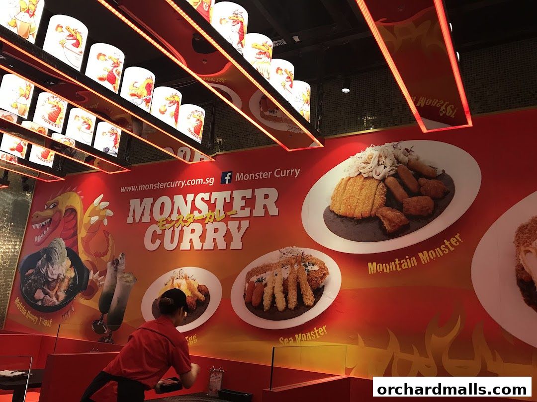 Interior of Monster Curry restaurant with a large wall display of curry dishes and branding.