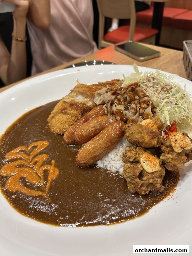 A plate of Japanese curry with rice, fried chicken, sausages, and shredded cabbage.