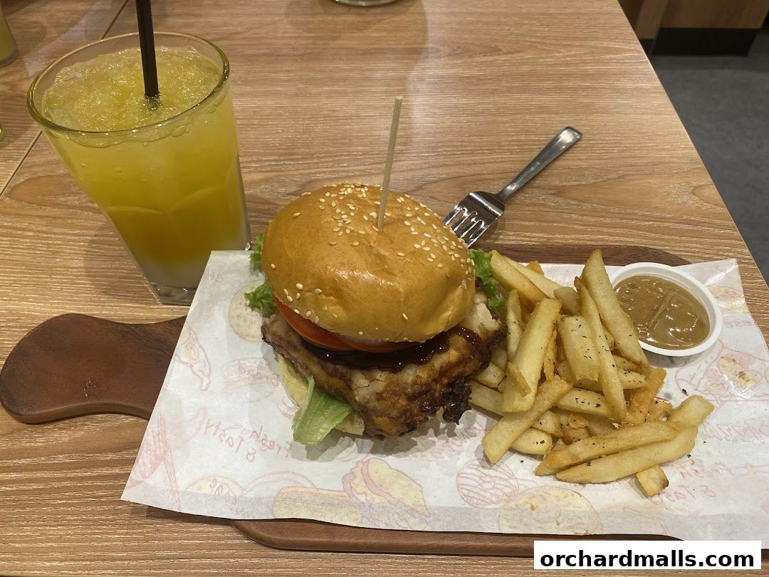 A juicy burger with fries and a refreshing drink on a wooden table.