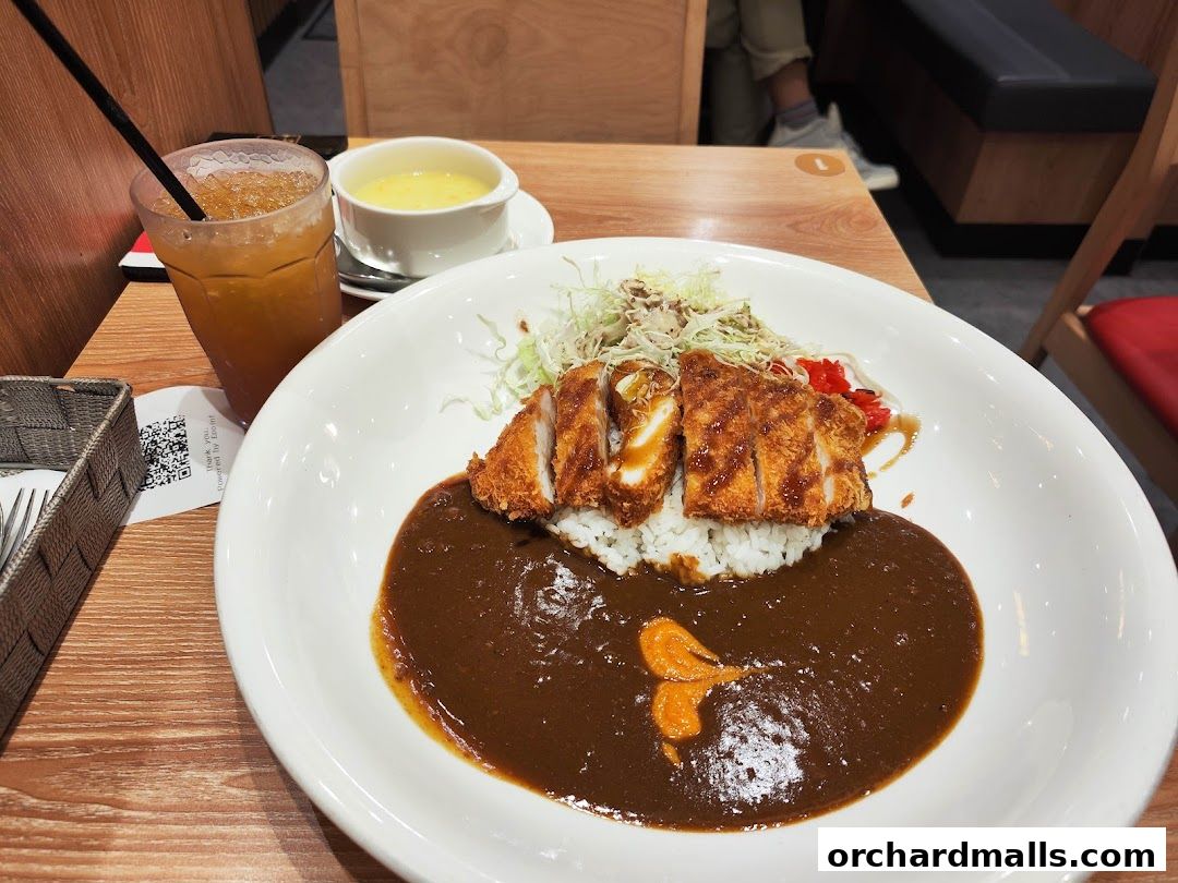 A delicious plate of Japanese curry with katsu, rice, and a side of soup and iced tea.