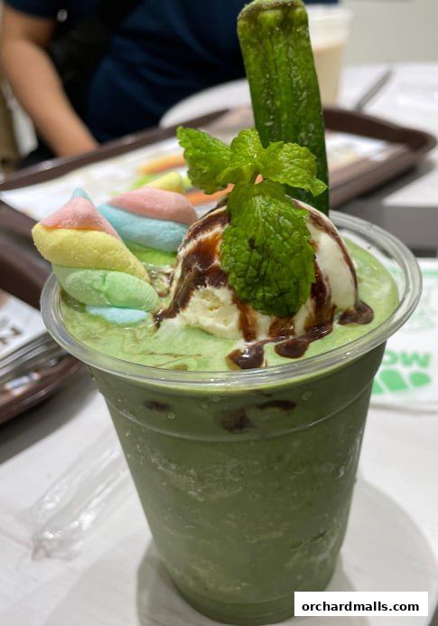 A delicious green smoothie topped with ice cream, marshmallows, and chocolate sauce.