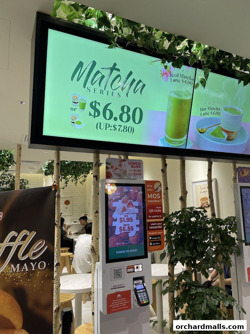 A MOS Burger shop interior featuring a digital menu board advertising a Matcha Series and a self-order kiosk.