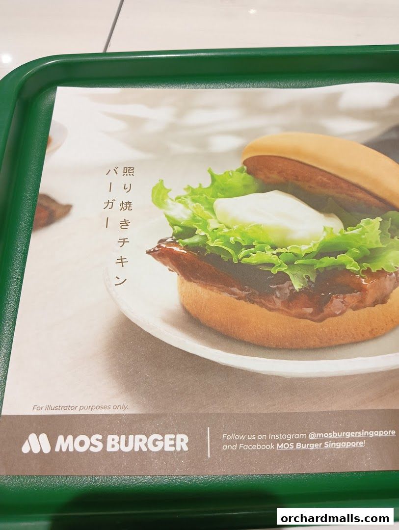 A close-up of a delicious MOS Burger Teriyaki Chicken burger on a white plate.
