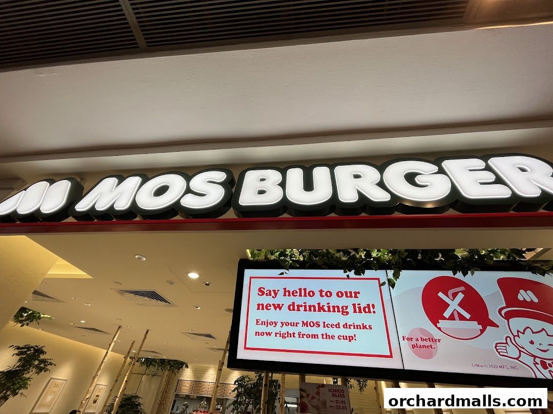 The MOS Burger sign is illuminated above a digital menu board advertising a new drinking lid.