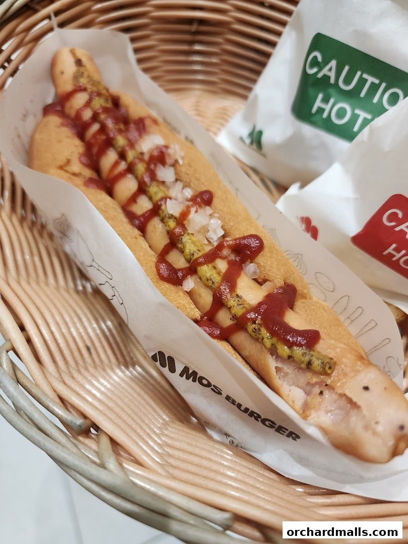 A close-up of a delicious MOS Burger hot dog with ketchup and mustard in a basket.