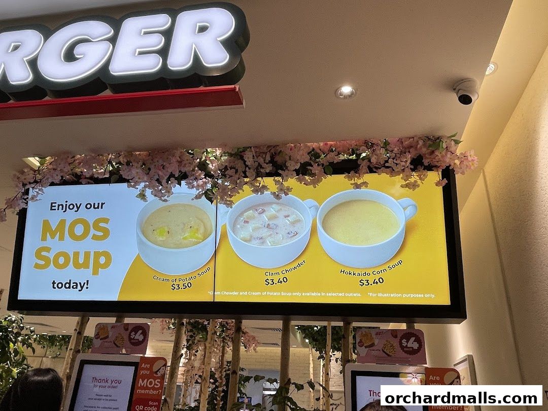 A digital menu board at MOS Burger showcasing three types of soup with prices.