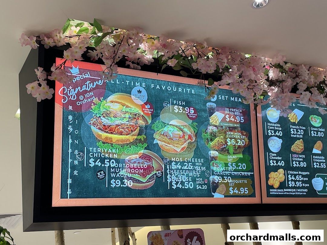 A menu board for MOS Burger featuring various burgers, sets, and sides, decorated with cherry blossoms.