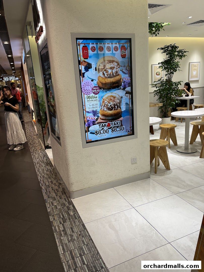 A digital menu board displays MOS Burger's Takoyaki and Matcha Mooncake offerings.