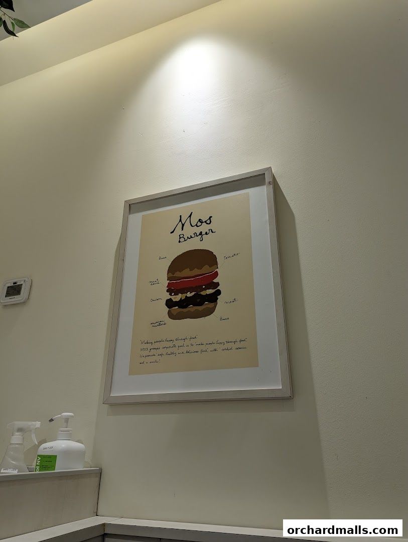 A framed illustration of a MOS Burger with ingredients labeled, hanging on a wall.