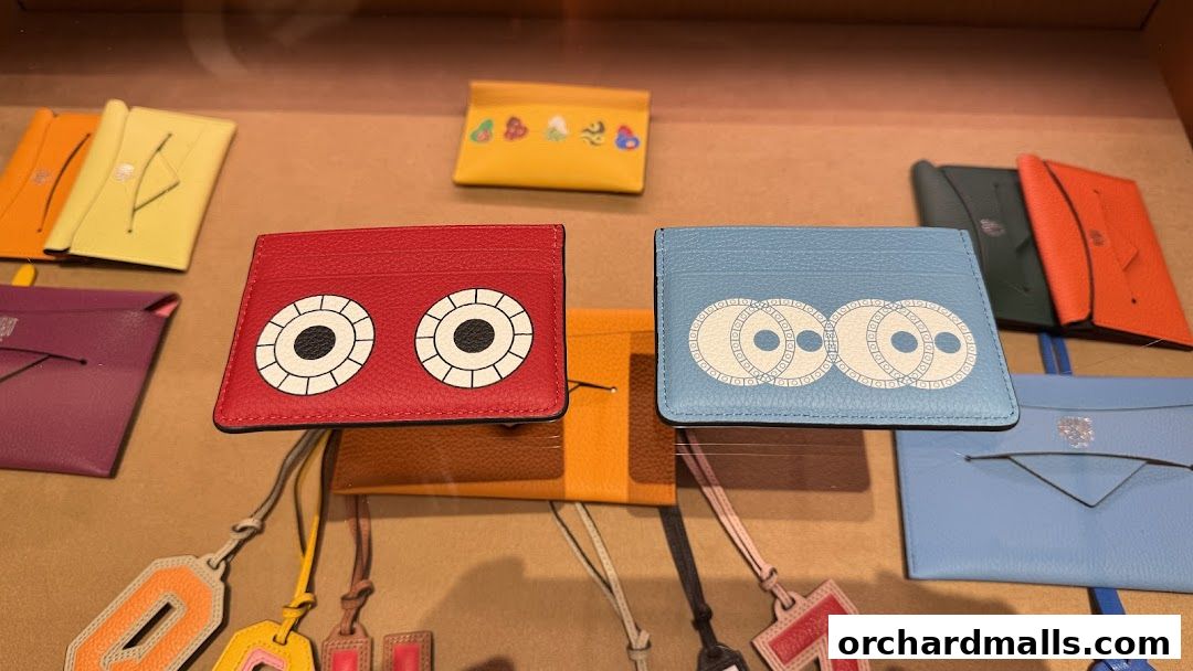 Colorful leather cardholders and pouches with playful designs displayed in a shop.