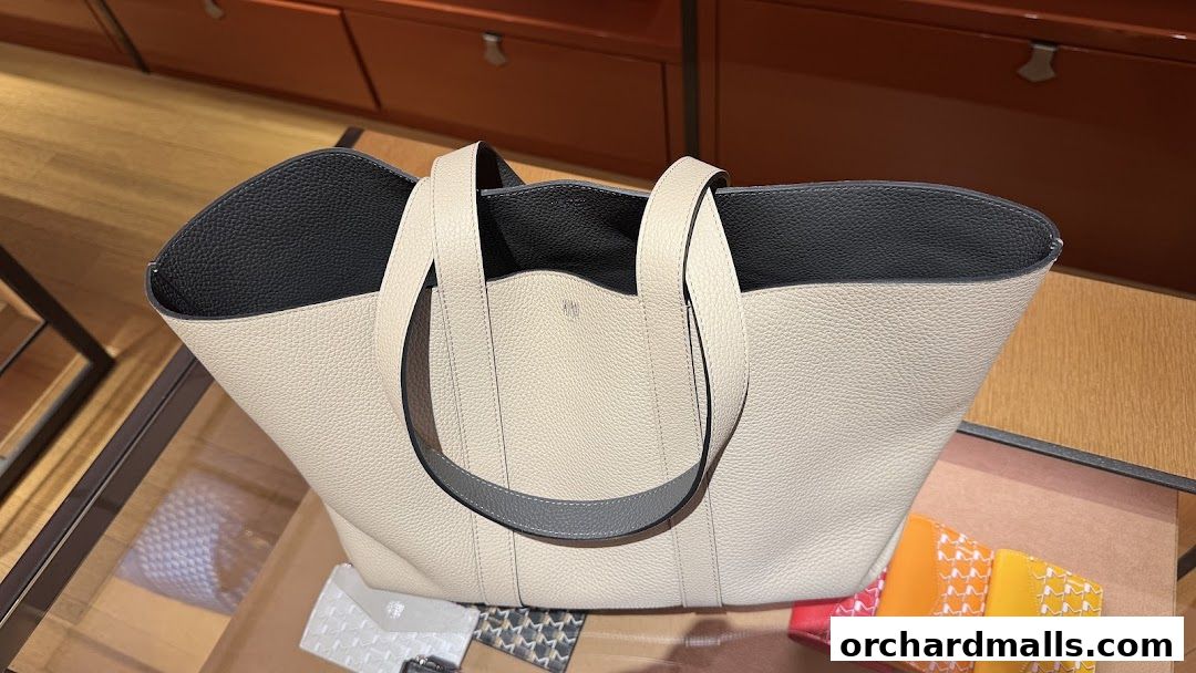 A close-up view of a luxurious beige leather tote bag with grey accents inside a shop.