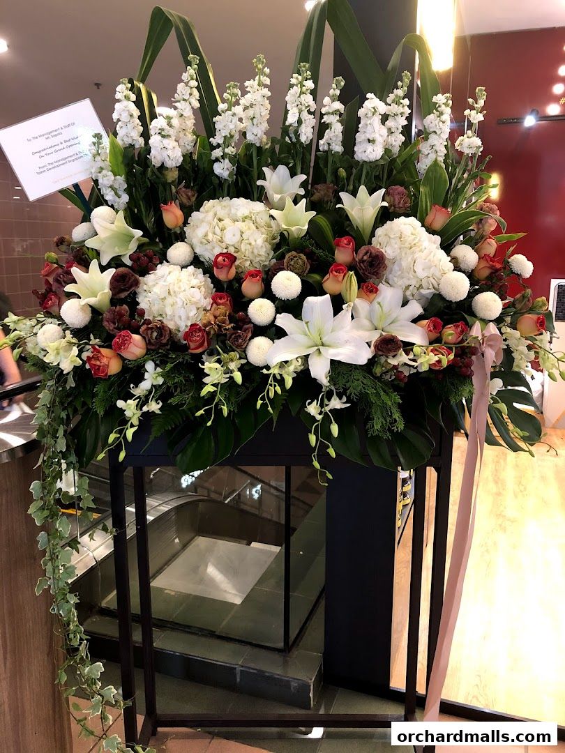 A large floral arrangement with white and pink roses, lilies, and greenery.