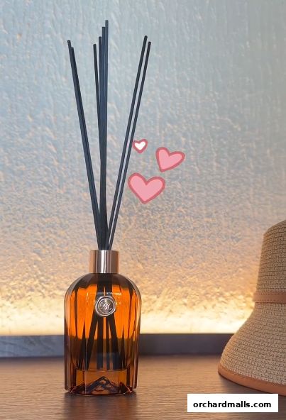 Aromatic diffuser with reeds in an amber glass bottle, with pink hearts and a hat.