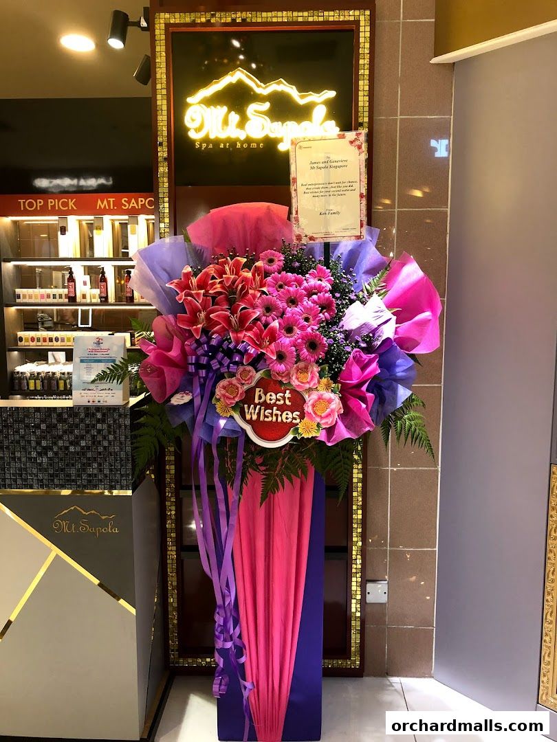 A floral arrangement with a 'Best Wishes' sign in front of the Mt. Sapola Spa at home store.