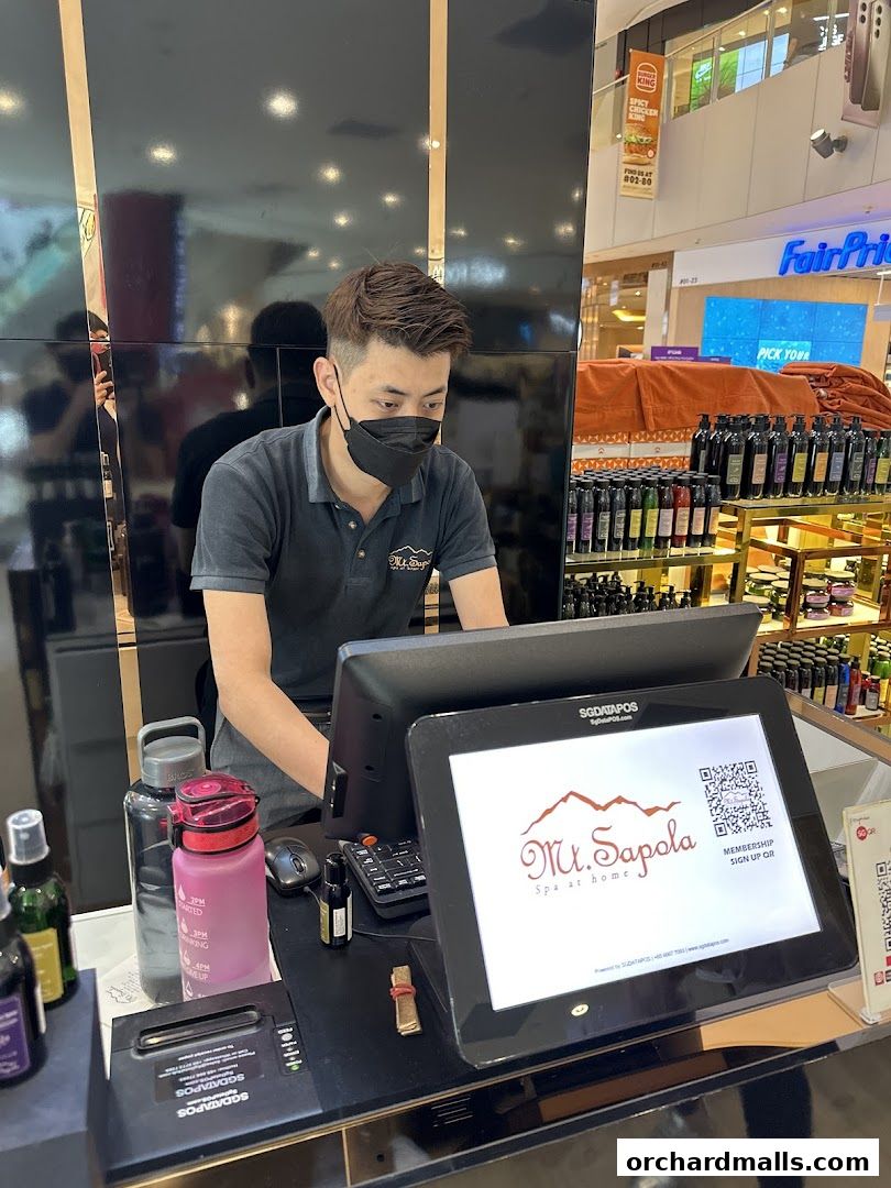 A staff member at Mt. Sapola Singapore is working at the counter with a computer and display screen.
