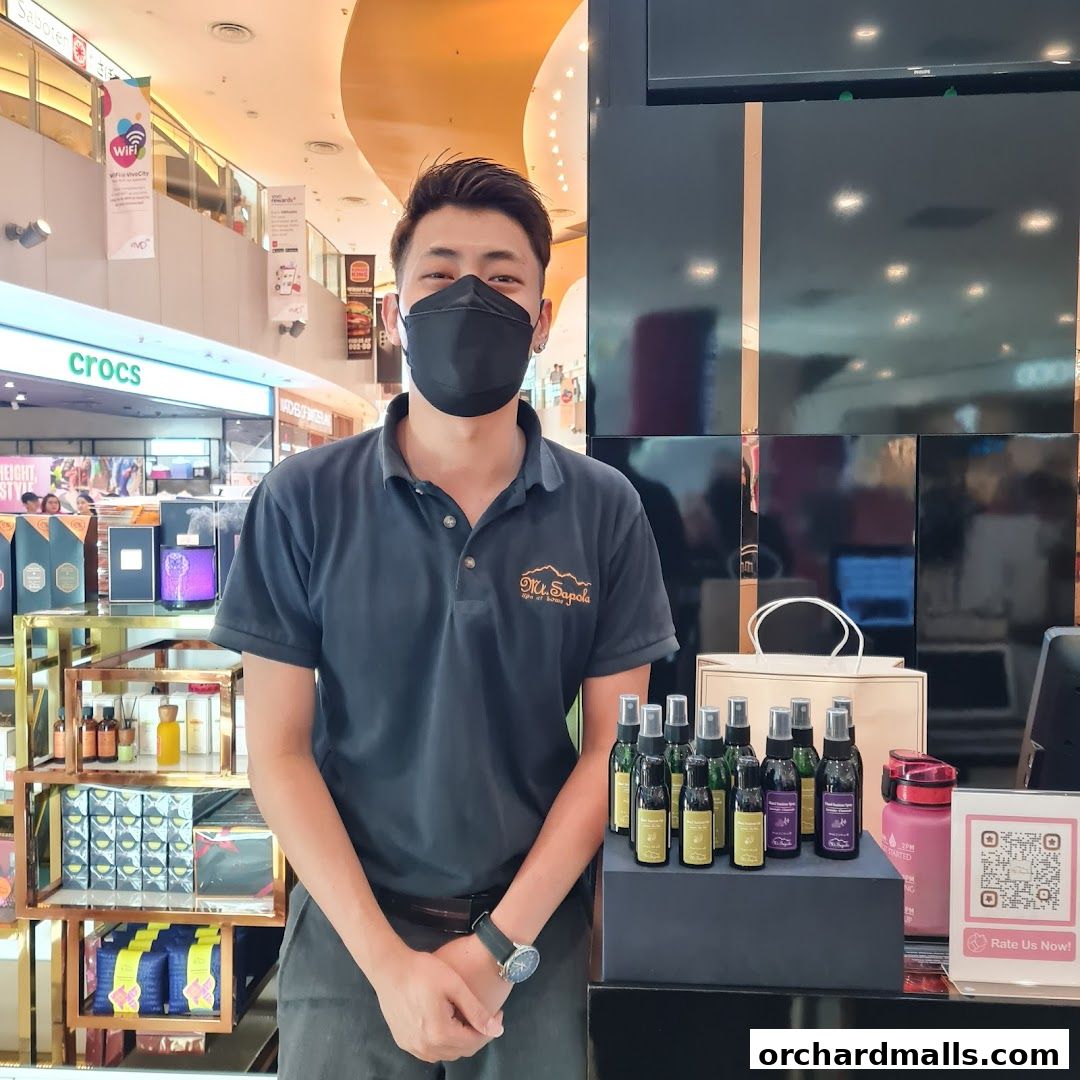 A staff member stands in front of a display of bottled products at Mt. Sapola Singapore.