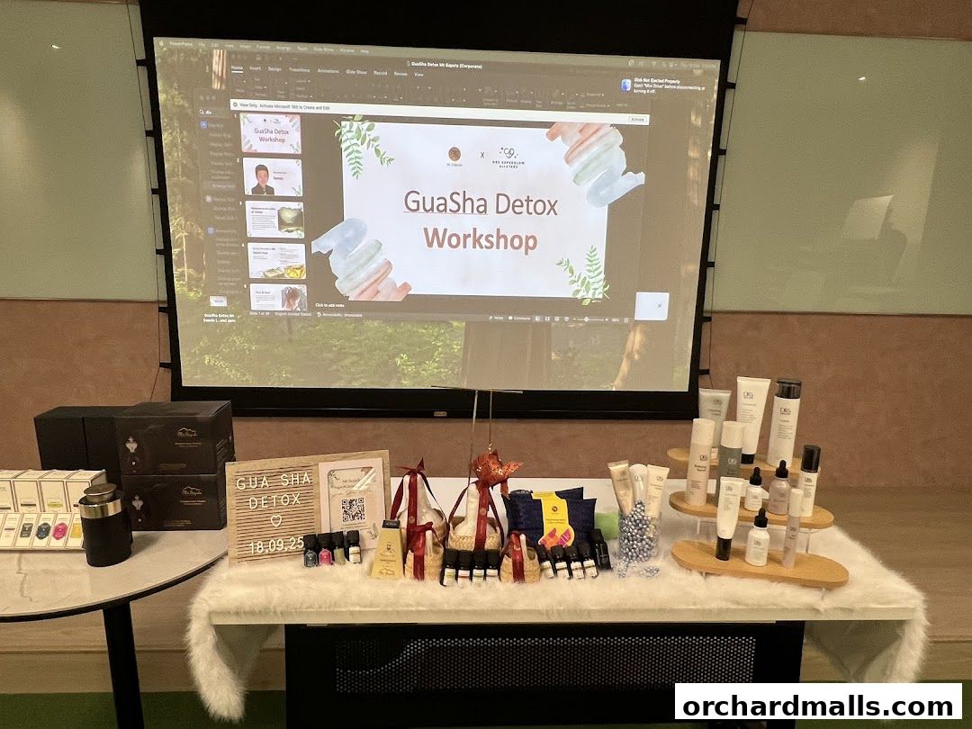 A display of skincare products and a presentation screen showing a Gua Sha Detox Workshop.