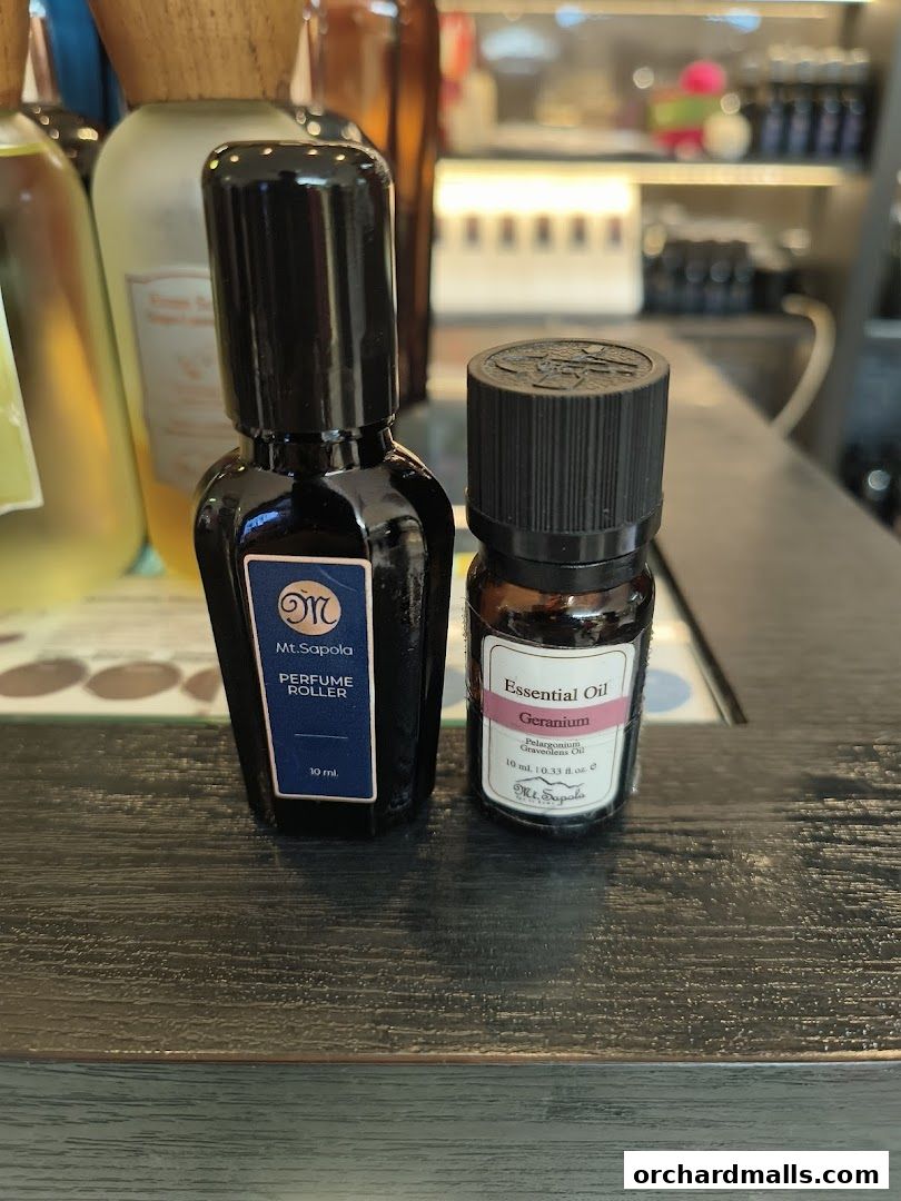 Two bottles of Mt. Sapola products, a perfume roller and essential oil, displayed on a wooden surface.