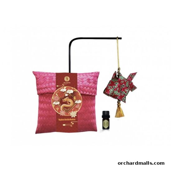 A pink woven sachet with a dragon motif, a small essential oil bottle, and a decorative fish ornament.