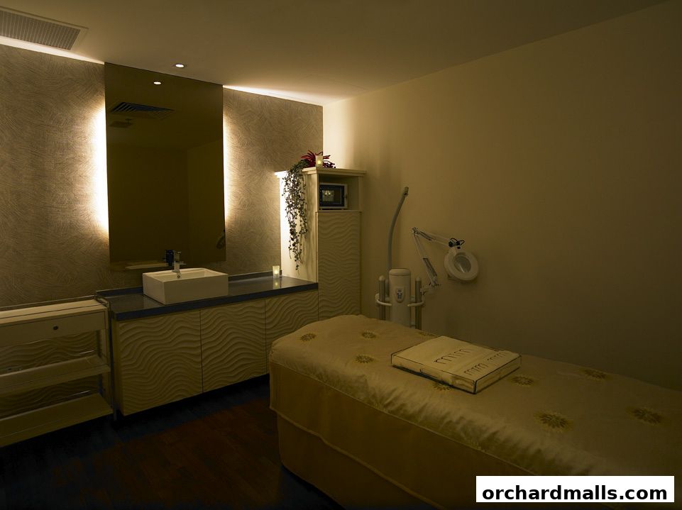 A treatment room with a massage bed, sink, and beauty equipment.