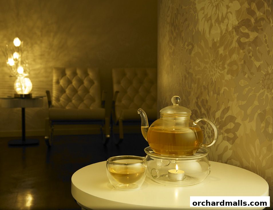 A teapot and cup of tea are displayed on a table with chairs in the background.