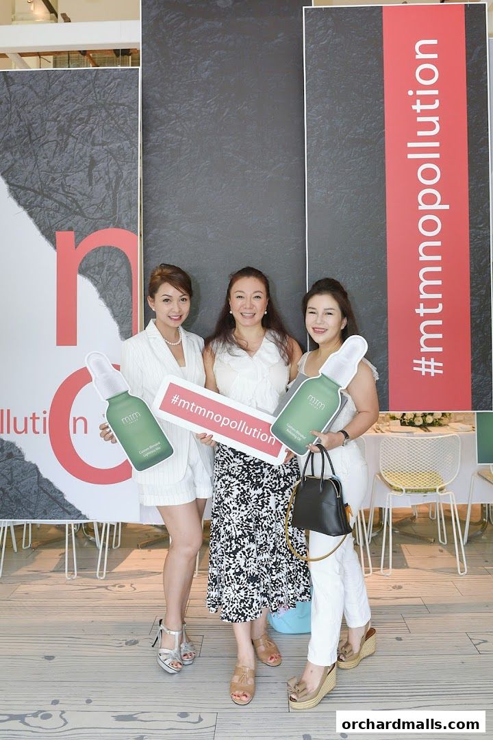 Three women pose with product cutouts and signs at an mtm labo event.