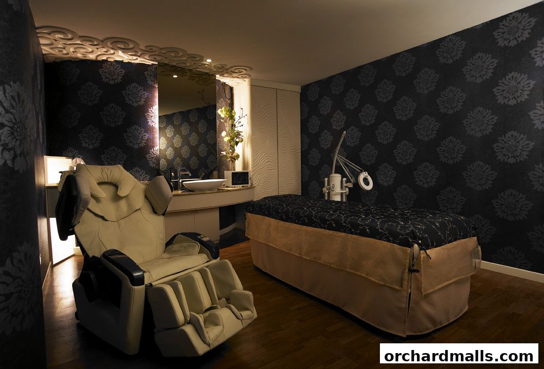A luxurious spa room with a massage chair, treatment bed, and sink.