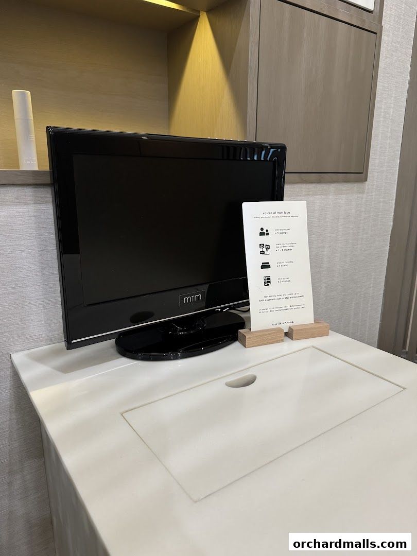 A television screen with a sign detailing a loyalty program next to it.