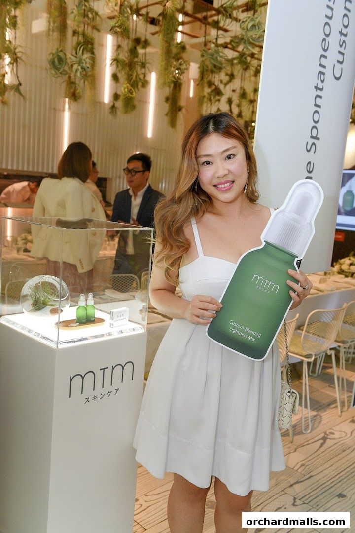 A woman holds a cutout of a skincare bottle at an mtm labo event.