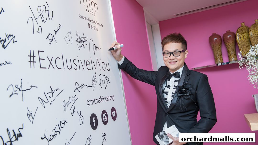 A man in a tuxedo signs a wall with #ExclusivelyYou and other signatures.