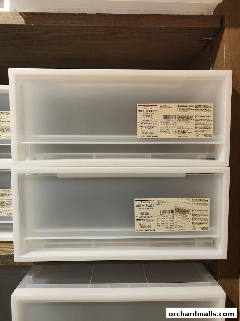 Two white MUJI storage boxes with labels are stacked on a shelf.