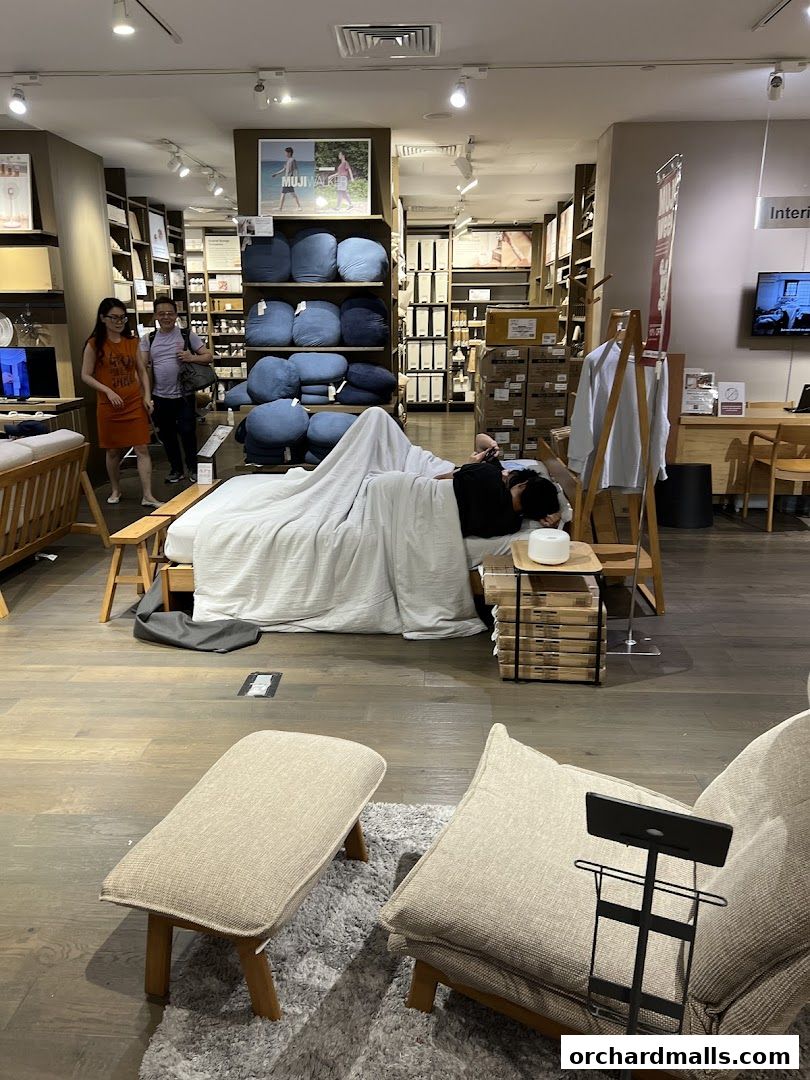 Interior view of MUJI ION Orchard showcasing furniture, bedding, and home goods with shoppers.