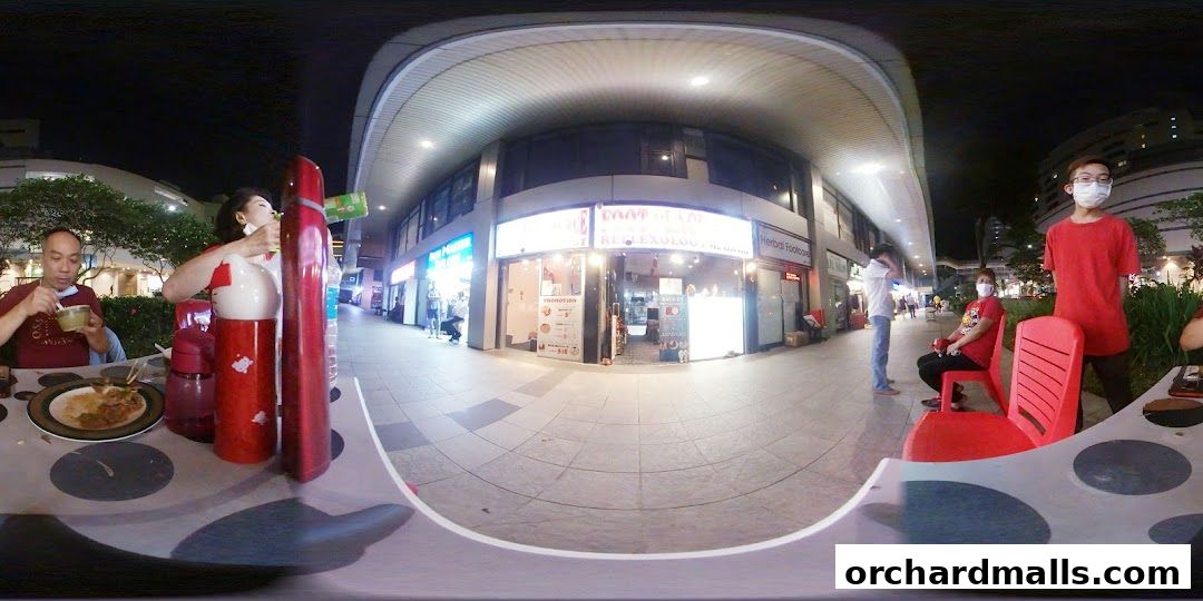 Exterior of 'My Foot Place Reflexology' shop at night with people dining nearby.