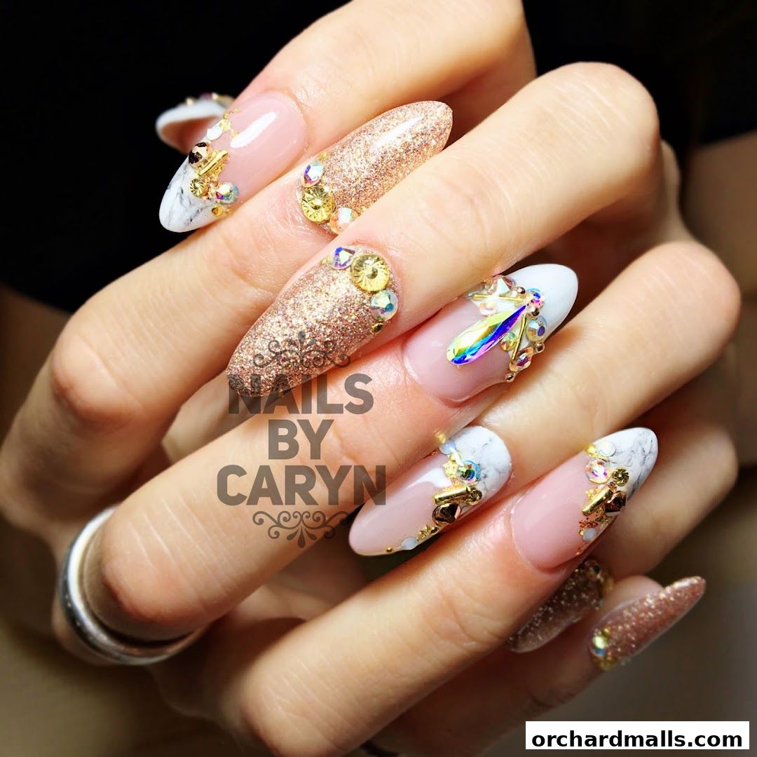 Close-up of hands with elaborately decorated nails featuring glitter, gems, and marble patterns.