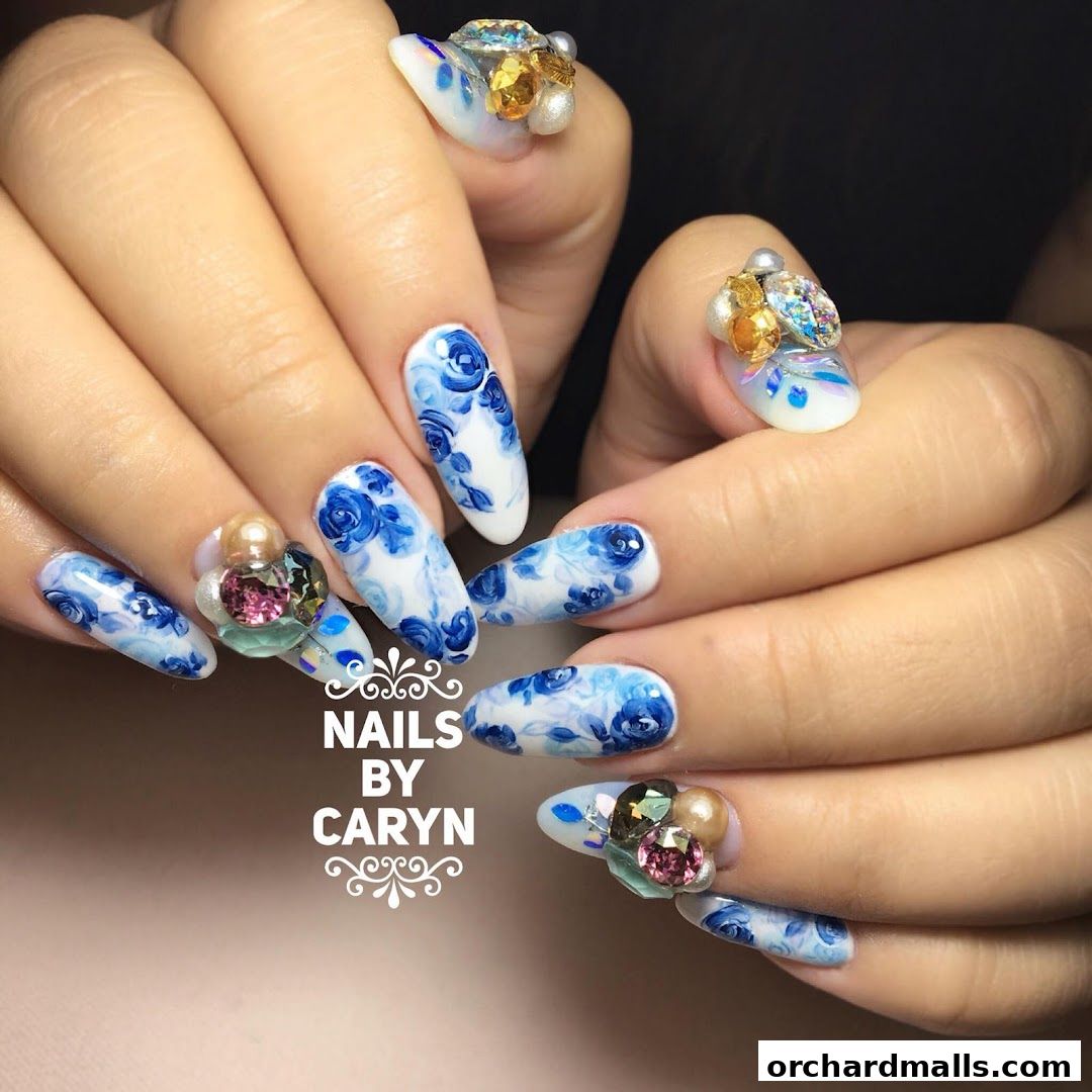 Close-up of hands with intricately designed blue floral pattern and jeweled nails.