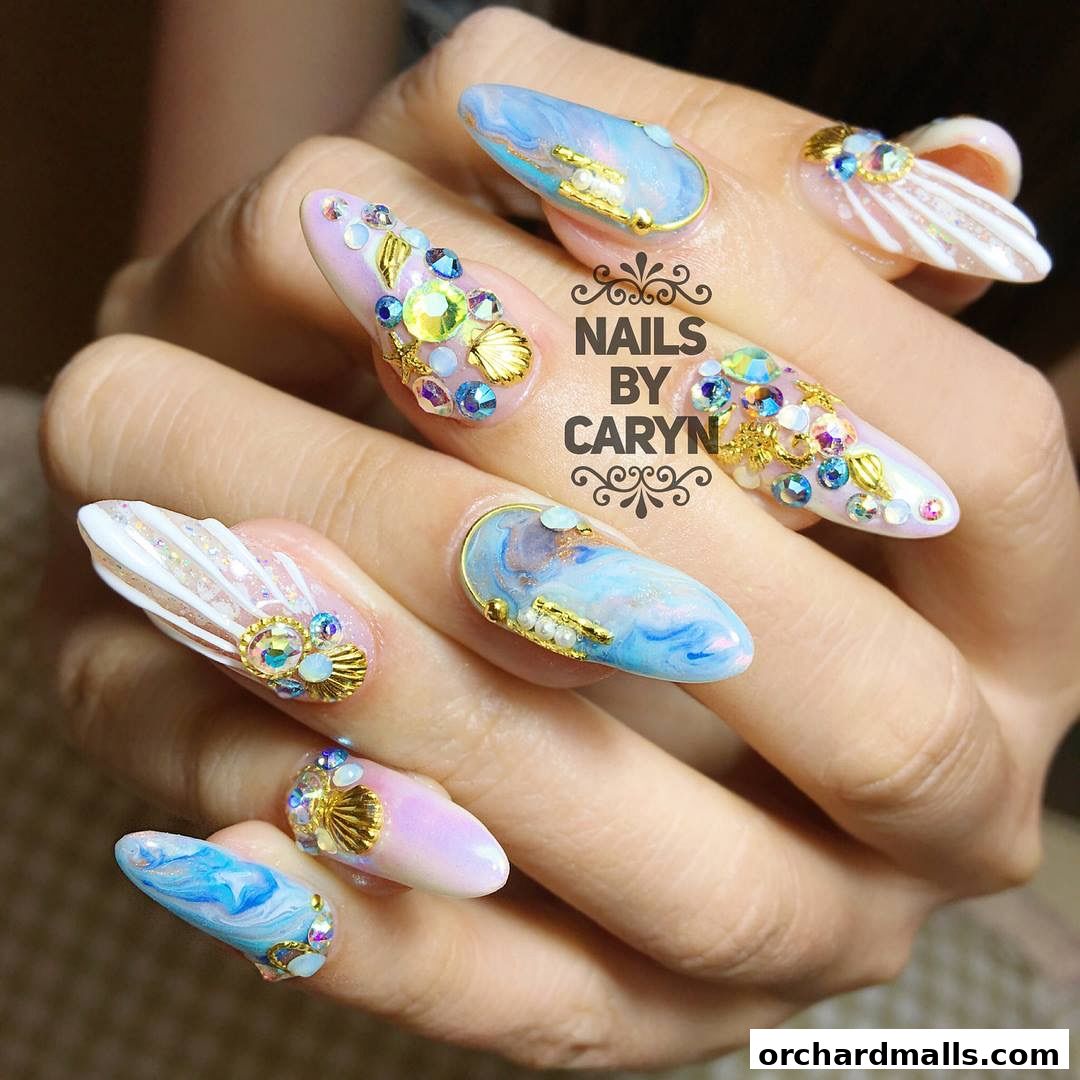 Close-up of hands with elaborate, jewel-encrusted, ocean-themed acrylic nails.