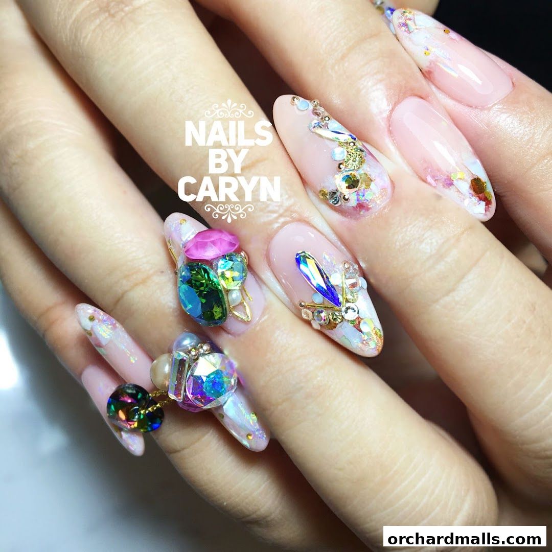 Close-up of hands with elaborate, jewel-encrusted nail art from Nails by Caryn.