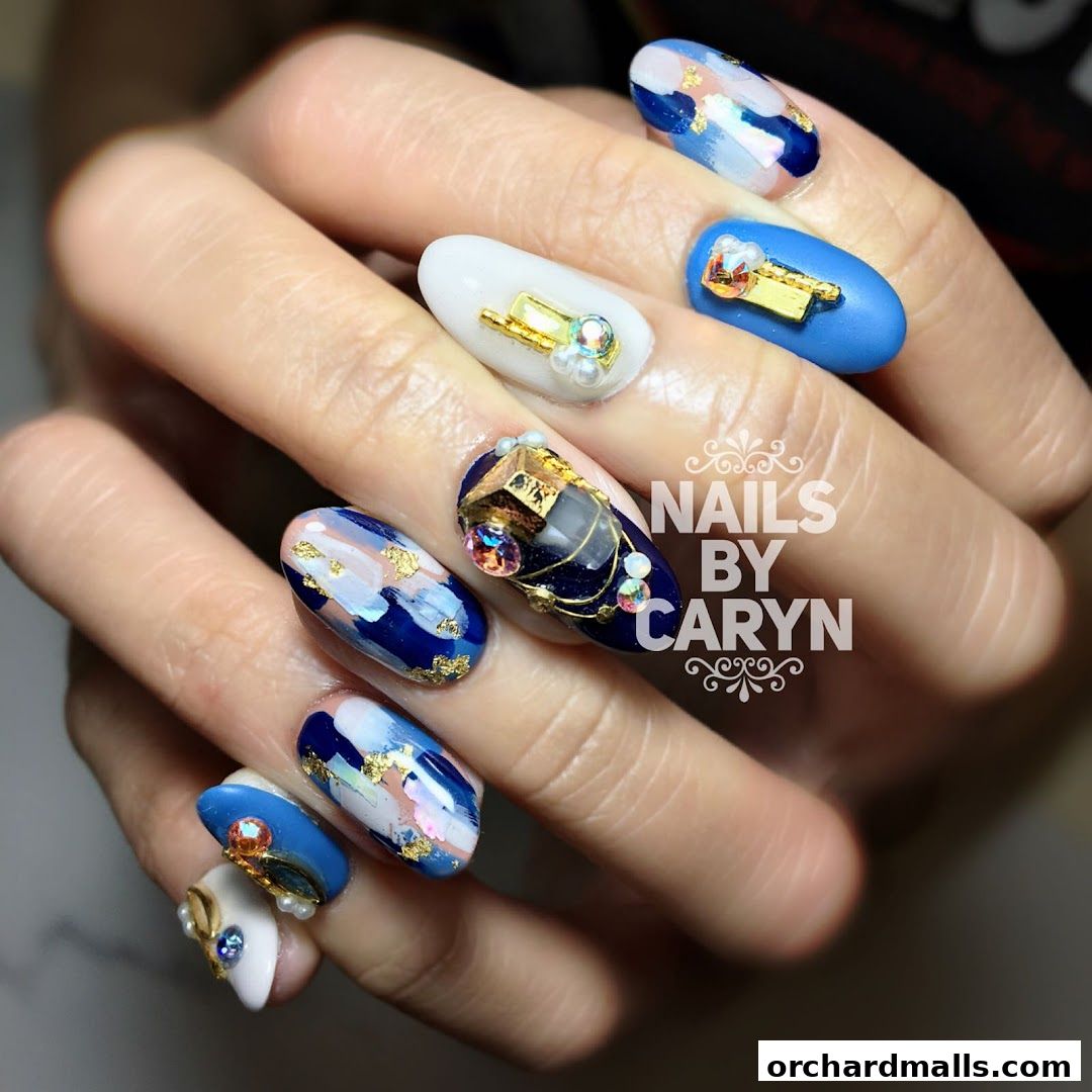 A hand showcasing intricate nail art with blue, white, and gold designs, adorned with gems.
