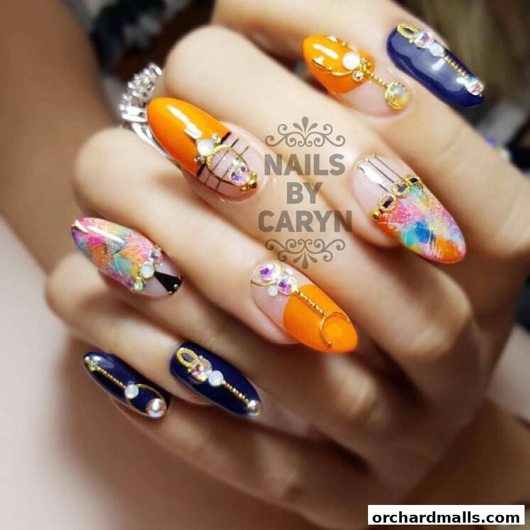 Close-up of a hand showcasing intricately designed nails with orange, navy, and abstract patterns.