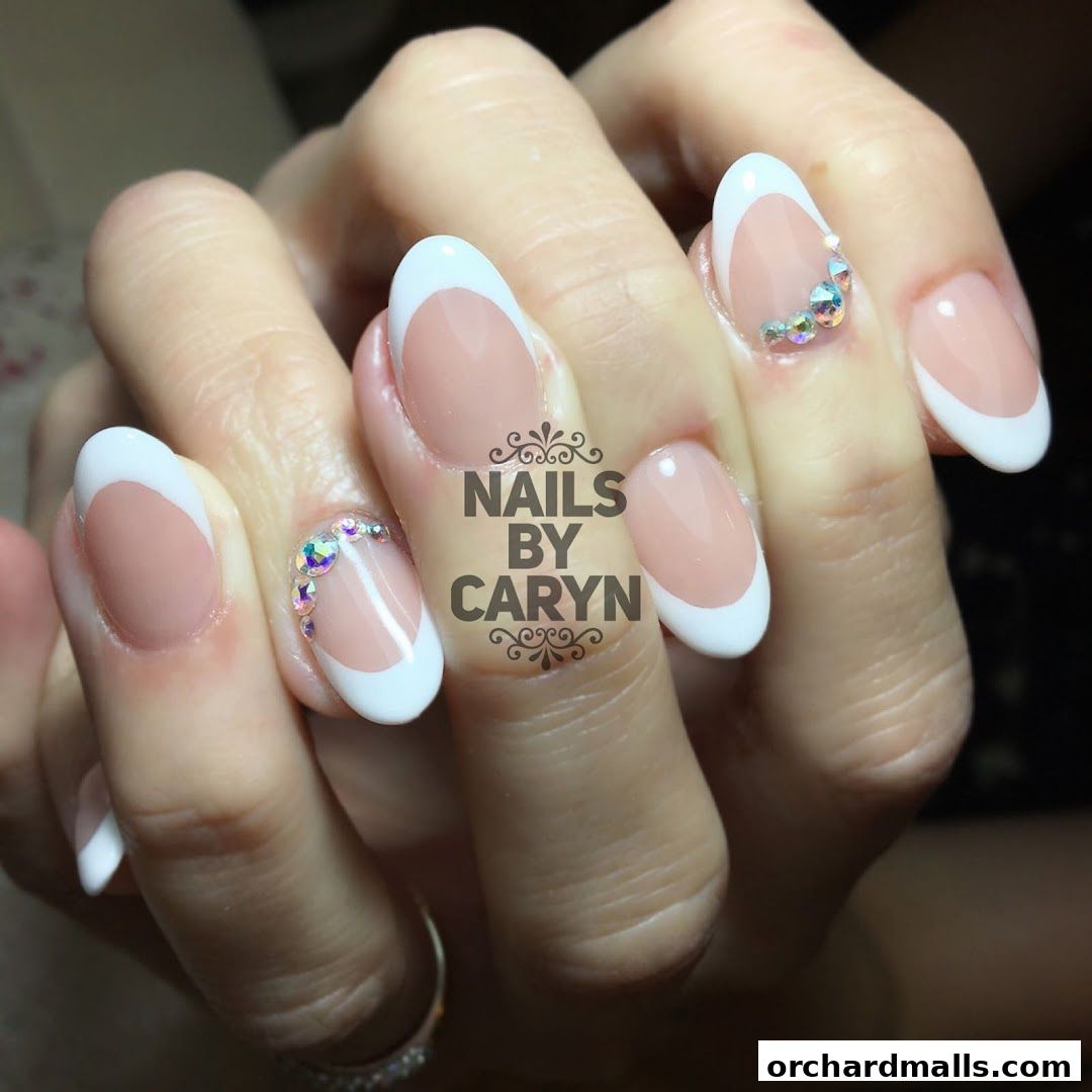 Close-up of hands with elegant French manicured nails adorned with rhinestones.