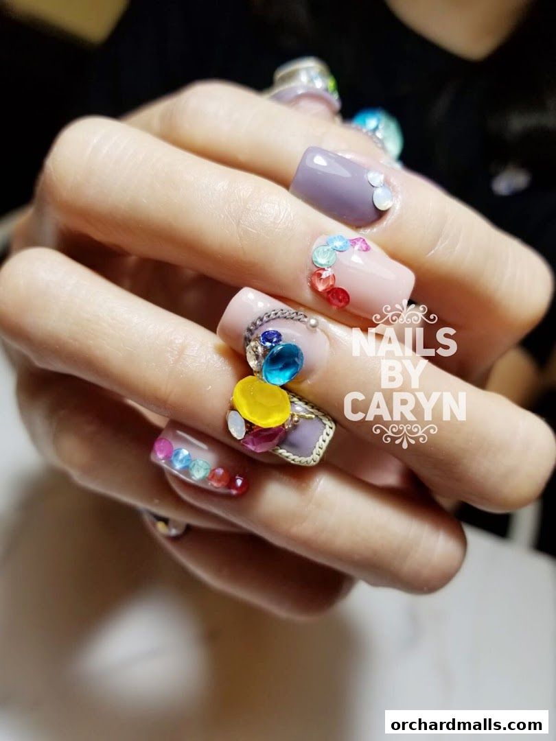 Close-up of a hand with elaborately decorated nails featuring colorful gems and charms.