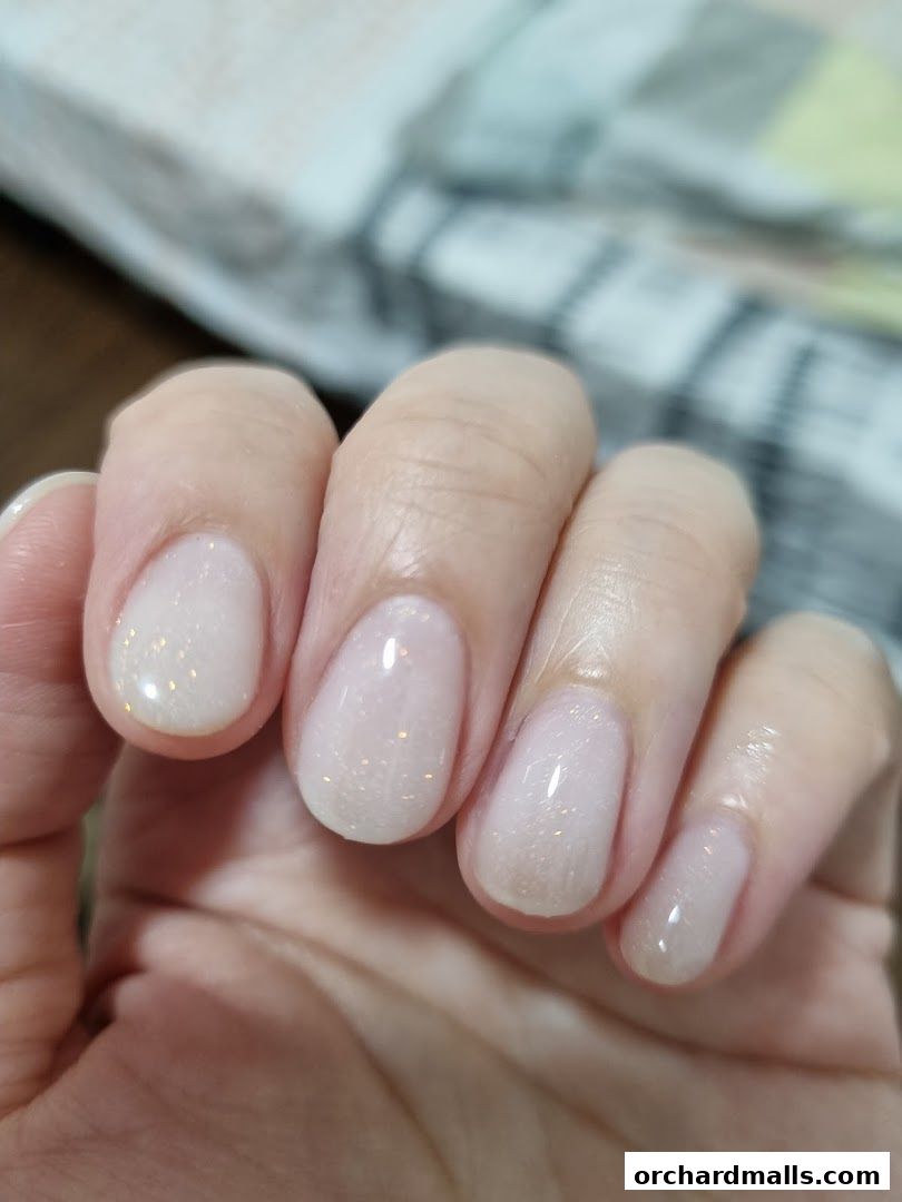 Close-up of a hand with neatly manicured nails featuring a subtle glitter polish.