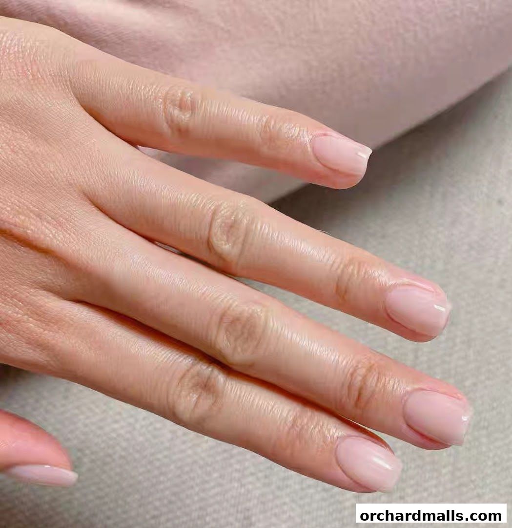 A close-up shot of a person's hand with perfectly manicured, light pink nails.