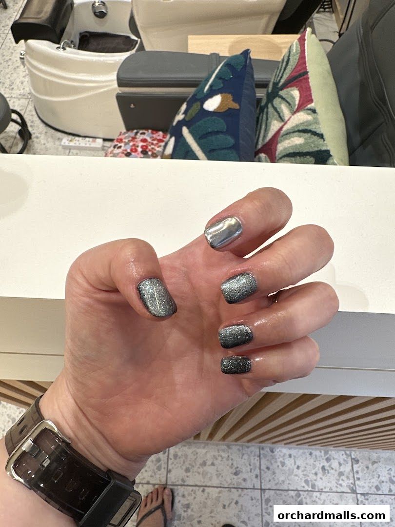 A close-up of a hand with sparkling grey and silver ombre nails.
