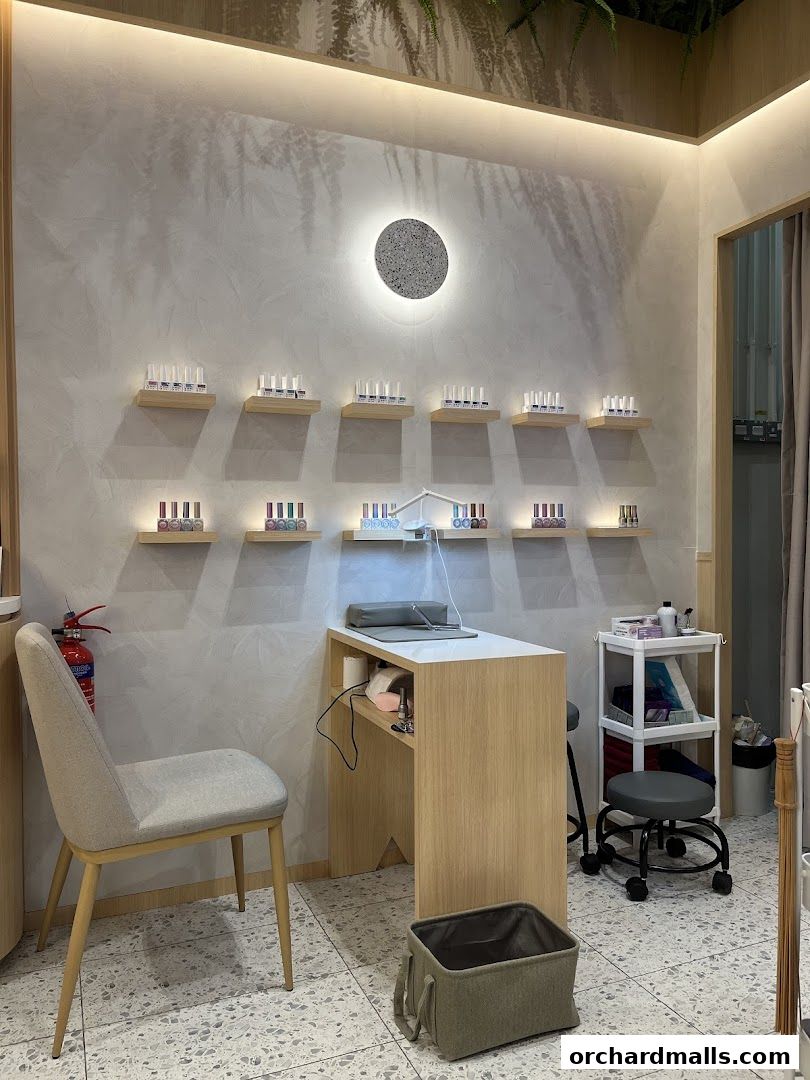 Interior of a nail salon with shelves displaying nail polish bottles and a manicure station.