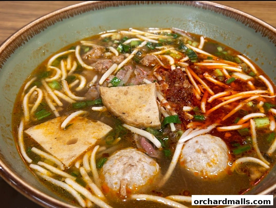 A close-up shot of a steaming bowl of Vietnamese noodle soup with meat and vegetables.
